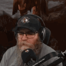 a man with a beard wearing headphones and a hat with a horse on it