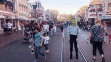 a crowd of people walking down a street with a sign that says ' disney store '