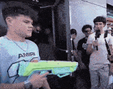 a man wearing a shirt that says amiri holding a water gun