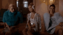 three women are sitting next to each other in a room wearing fur coats and ear muffs .
