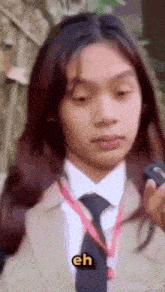 a woman in a suit and tie is holding a cell phone .