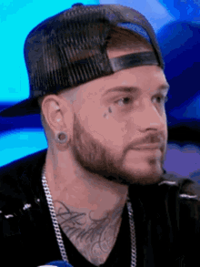 a man with a tattoo on his face is wearing a hat