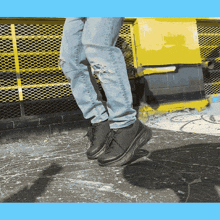 a person wearing ripped jeans and black shoes is jumping