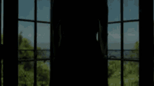 a woman in a black dress is standing on a balcony looking out of a window .