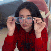 a woman wearing a red hoodie and glasses with the letters ng on the bottom right