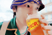 a man wearing a hat is drinking from a bottle that says " teor " on it