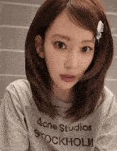 a woman wearing a acne studios stockholm shirt looks at the camera