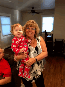 a woman is holding a baby in a pink pajama