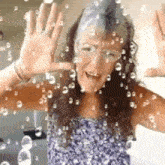 a woman is standing in front of a window with her hand up .