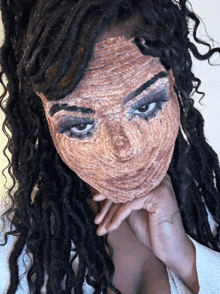 a woman with dreadlocks is wearing a knitted mask on her face