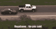 a white truck is towing a black car on a road with the words royalzone / do pas cukl