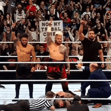 a man in a wrestling ring holds up a sign that says no my tribal cie