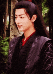 a man with long hair is wearing a black vest and a red shirt