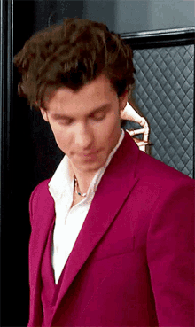 a close up of a man wearing a red suit and white shirt