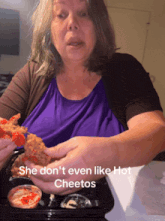 a woman eating cheetos with a caption that says she doesn 't even like hot cheetos