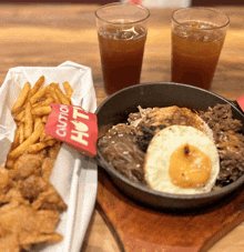 two glasses of iced tea next to a plate of food with a caution hot sign on it