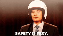 a man in a suit and tie wearing a helmet says " safety is sexy "