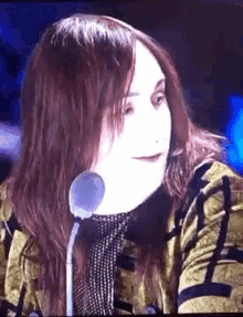 a woman with long hair is sitting in front of a microphone and smiling .