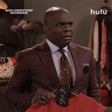 a man in a suit and tie is holding a red shirt with a tag that says " i do n't care "