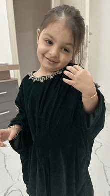 a little girl wearing a green dress is smiling