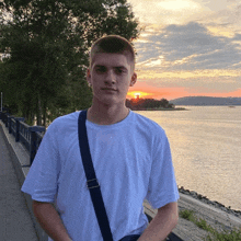 a man in a white shirt stands in front of a body of water