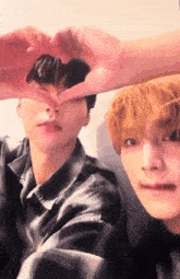 two young men make a heart with their hands