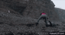 a woman is laying on the ground on a rocky beach .
