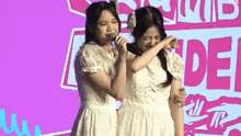 two girls are standing next to each other on a stage and one of them is crying .