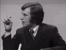 a man in a suit and tie is smoking a cigarette