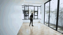 a woman is standing in a room with a lot of windows and a sign that says flexi room .