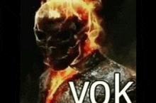 a ghost rider is standing in the dark with flames coming out of his head .