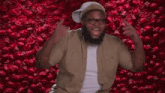 a man with glasses is standing in front of a wall of red roses .