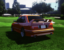 a red car with a california license plate is parked in the grass