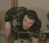 a man wearing headphones is squatting on the floor .