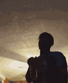 a man is standing in a dark room holding a bottle