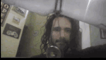 a man with long hair is taking a selfie in front of a wall with a motorcycle sign on it