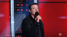 a man singing into a microphone with the word nbc on the bottom right