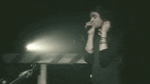 a man singing into a microphone with a light behind him