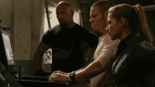 two men and a woman are looking at a computer screen and one of the men has a patch on his shoulder that says police