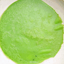 a green sauce is being cooked in a white pan on an elmich induction cooker