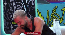 a man with blonde hair and a beard is laying on a bed in front of a graffiti wall .