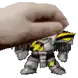 a hand is holding a toy robot with a yellow stripe on its chest .