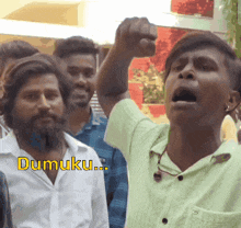 a man in a green shirt holds his fist in the air with the word dumuku written on the bottom