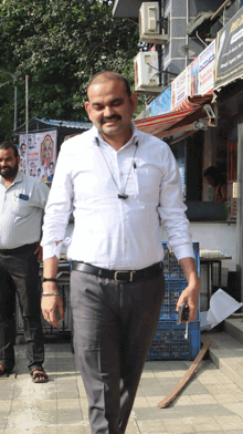 a man wearing a white shirt and black pants walks down a street