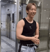 a man wearing a black tank top is smiling in front of a building that says trang