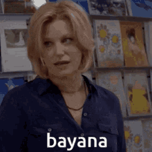 a woman in a blue shirt is standing in front of a display of greeting cards and says ' dayana '