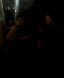 a couple of women standing next to each other in the dark