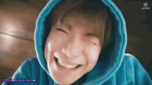 a close up of a person wearing a blue hoodie making a face .