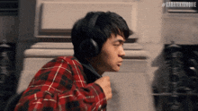 a man wearing headphones and a plaid shirt is running