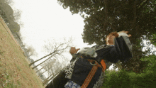 a man in a kimono stands in a park with trees in the background
